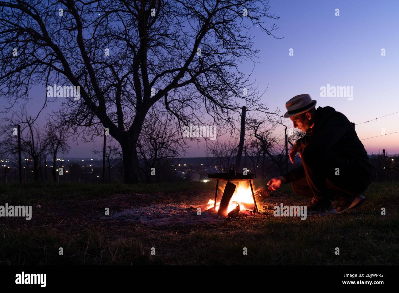 A man throws a firewood into the fire. Close up photo of bonfire in the