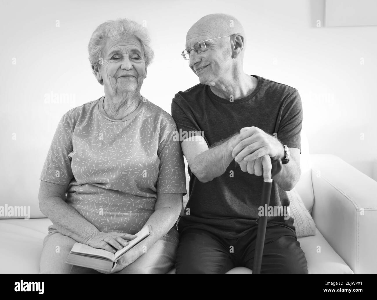 Senior people sitting on couch at home, black and white effect. Elderly care Stock Photo