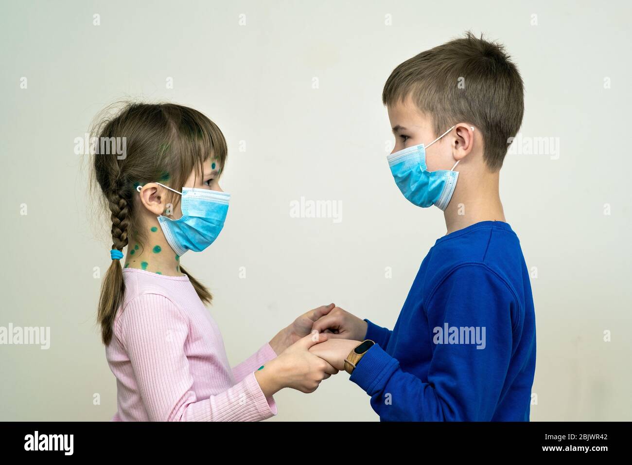 Boy and girl wearing blue protective medical mask ill with chickenpox, measles or rubella virus with rashes on body. Children protection during epidem Stock Photo