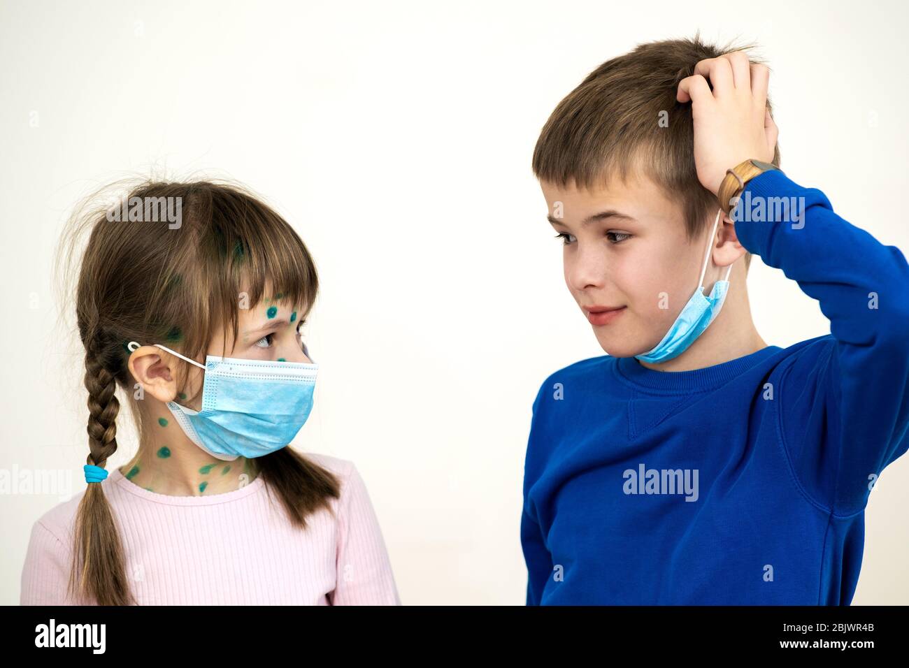 Boy and girl wearing blue protective medical mask ill with chickenpox, measles or rubella virus with rashes on body. Children protection during epidem Stock Photo