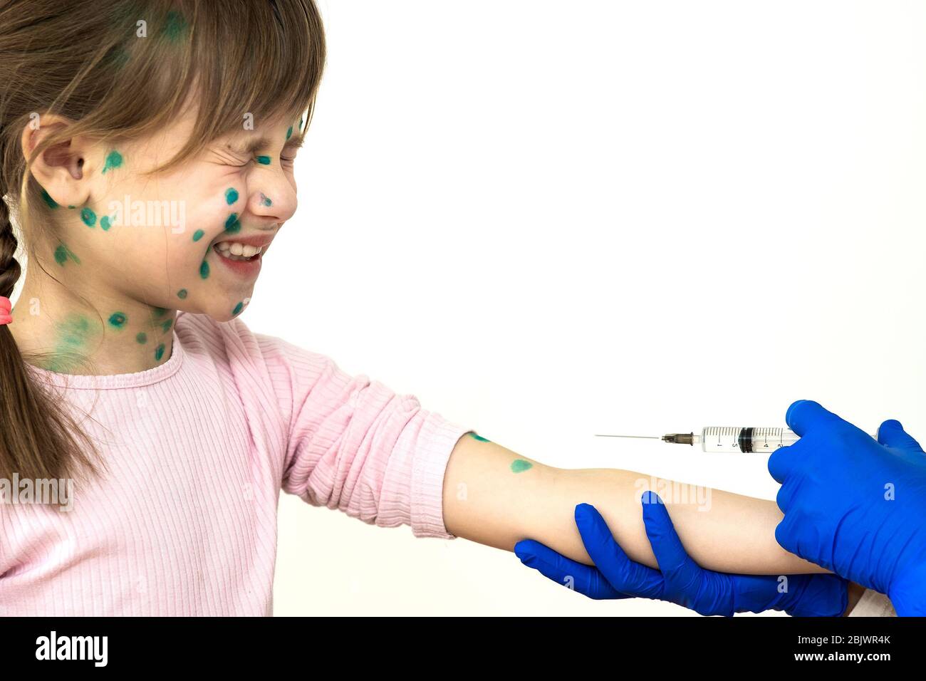 Doctor making vaccination injection to an afraid child girl sick with chickenpox, measles or rubella virus. Vaccination of children at school concept. Stock Photo
