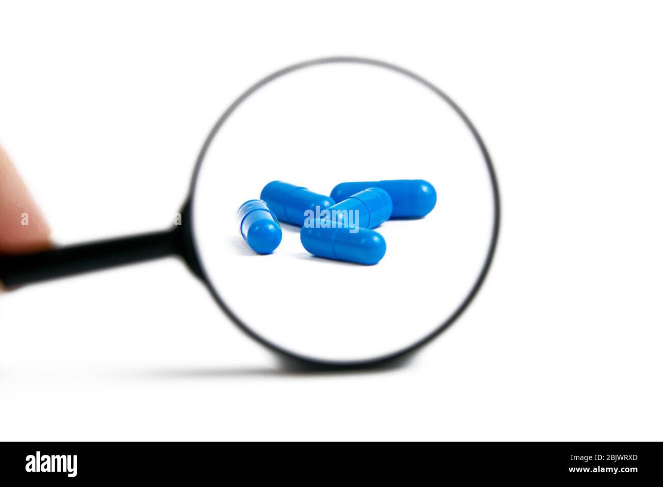 Zooming pills using magnifier glass. Special unique blue pill isolated on  white background Stock Photo - Alamy