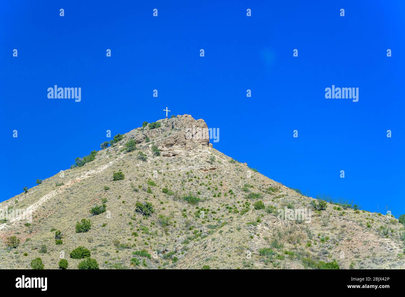 Lone white cross on top of rocky mountain Stock Photo