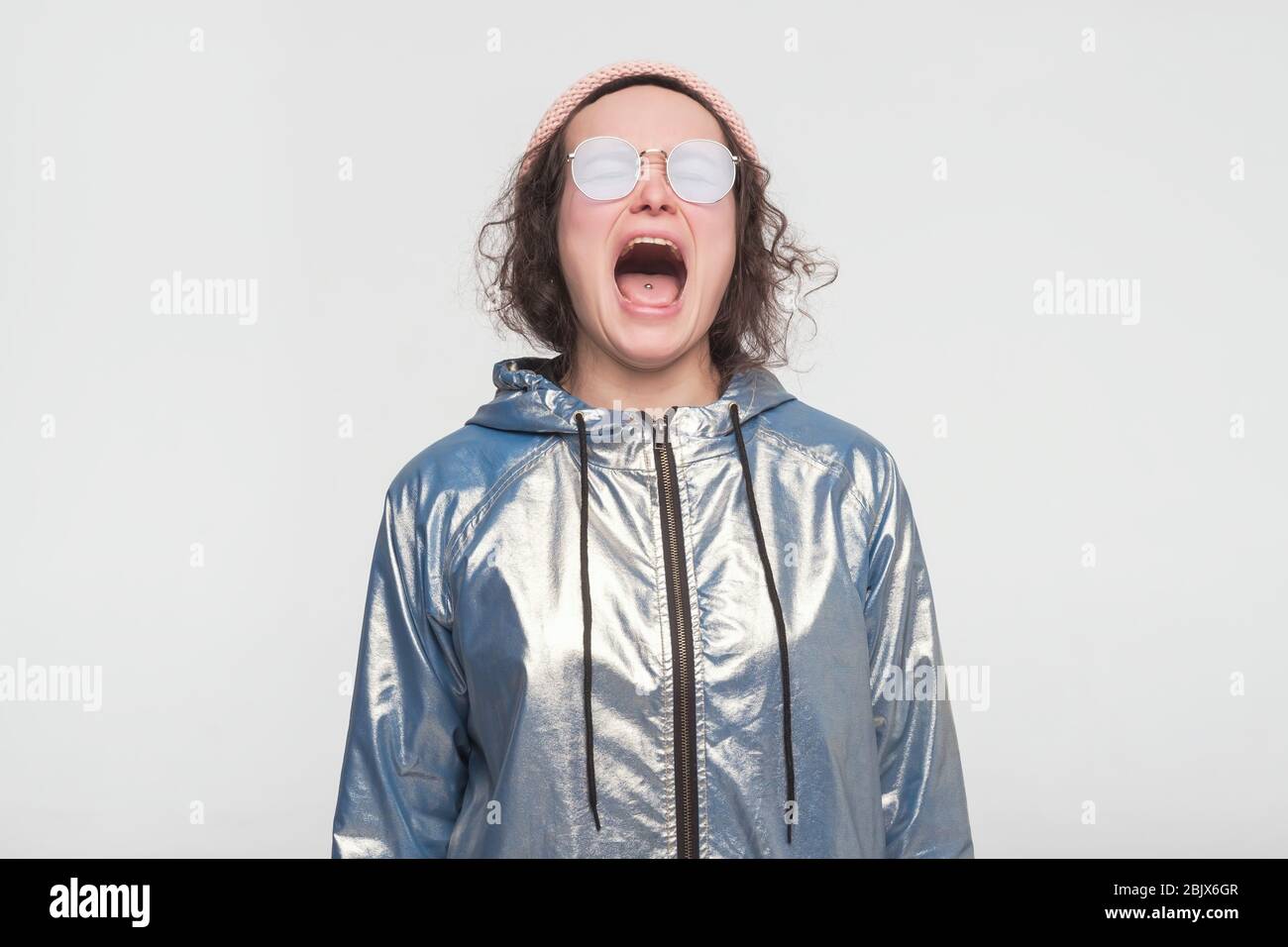 Emotional angry woman in silver coat and summerglasses screaming. Emotional, young face. Human emotions, facial expression concept. Stock Photo