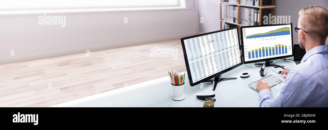 Analyst Looking At Data Table Report On Computer Desk Stock Photo
