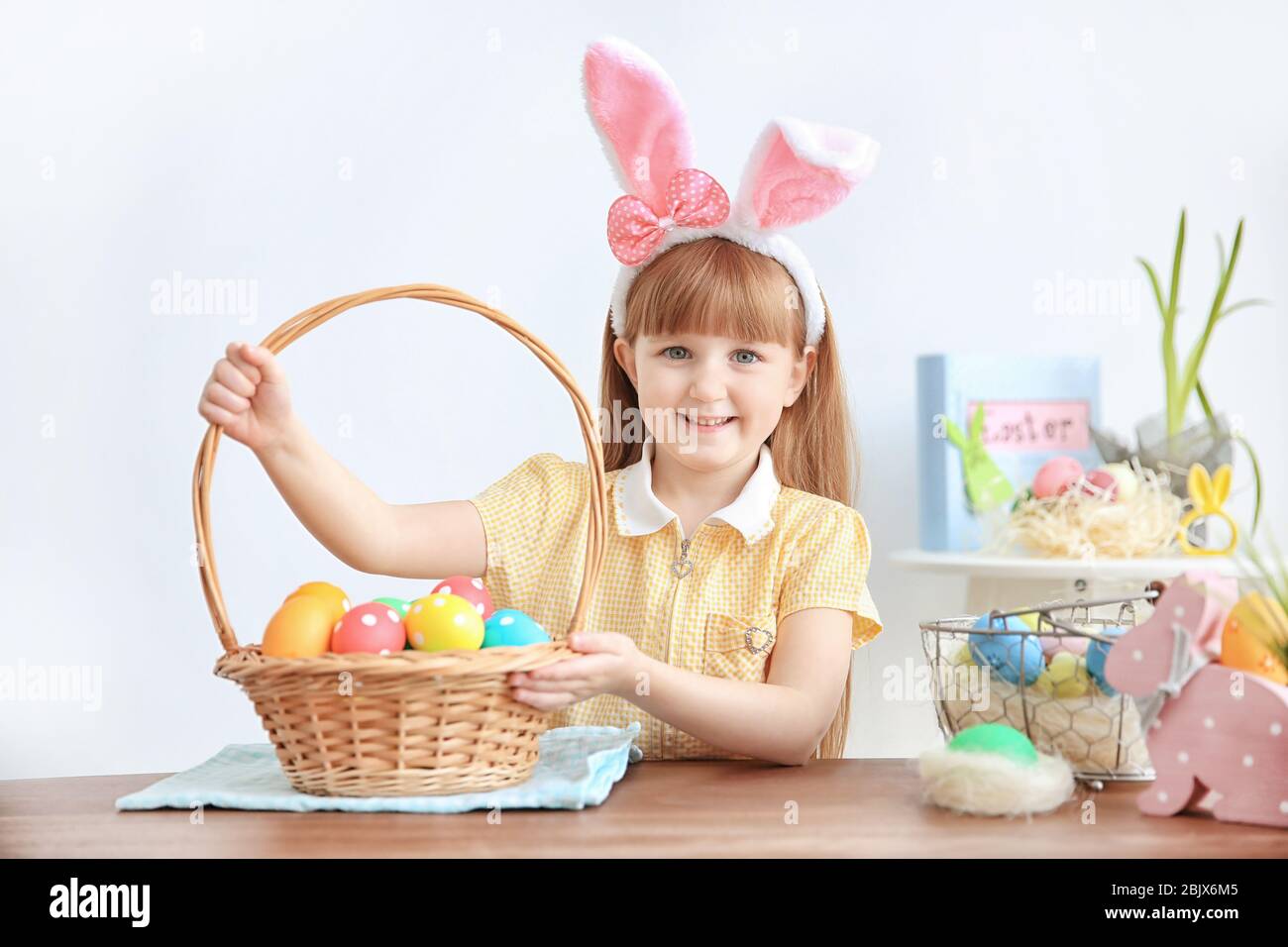 Cute little girl with bunny ears holding basket full of colorful Easter ...