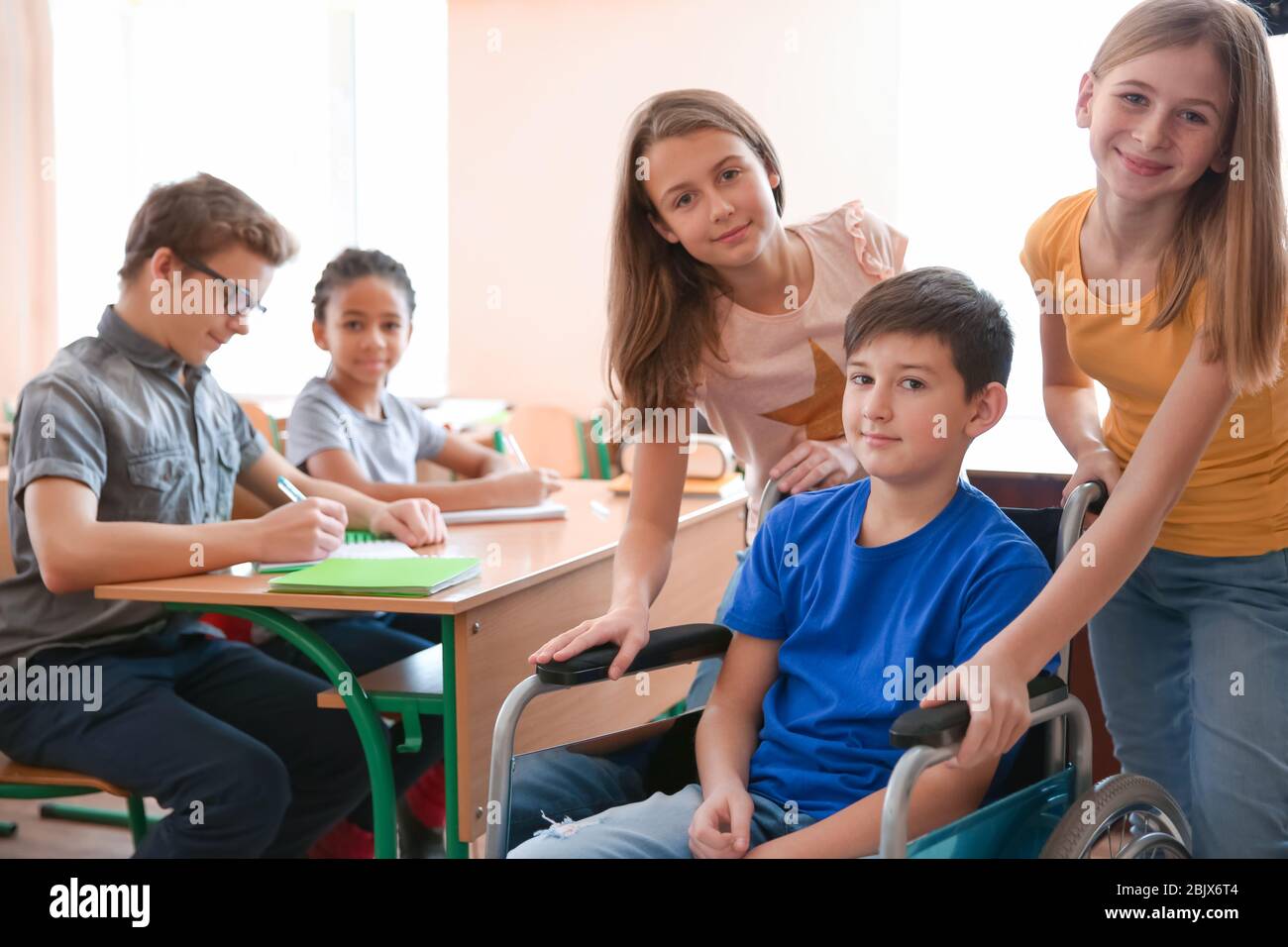 Boy in wheelchair with classmates at school Stock Photo