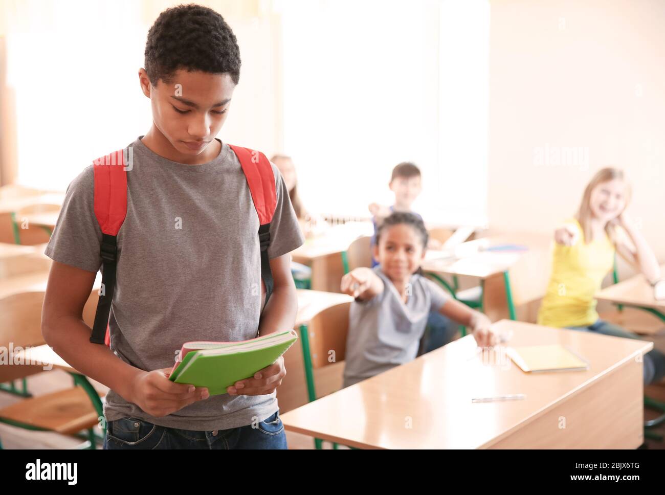 Sad African American teenage boy in classroom. Bullying at school Stock Photo