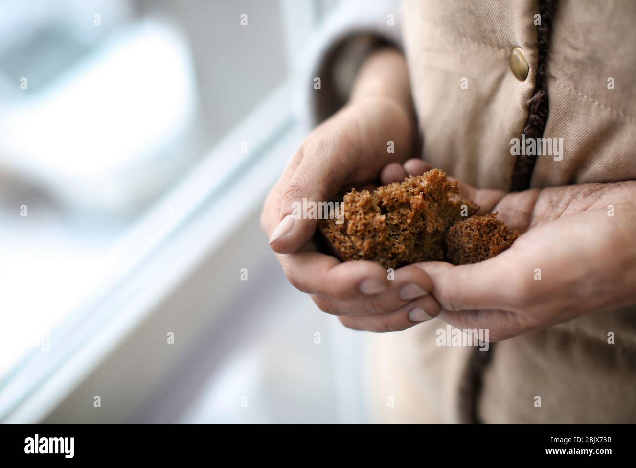 Poor woman holding bread on blurred background Stock Photo