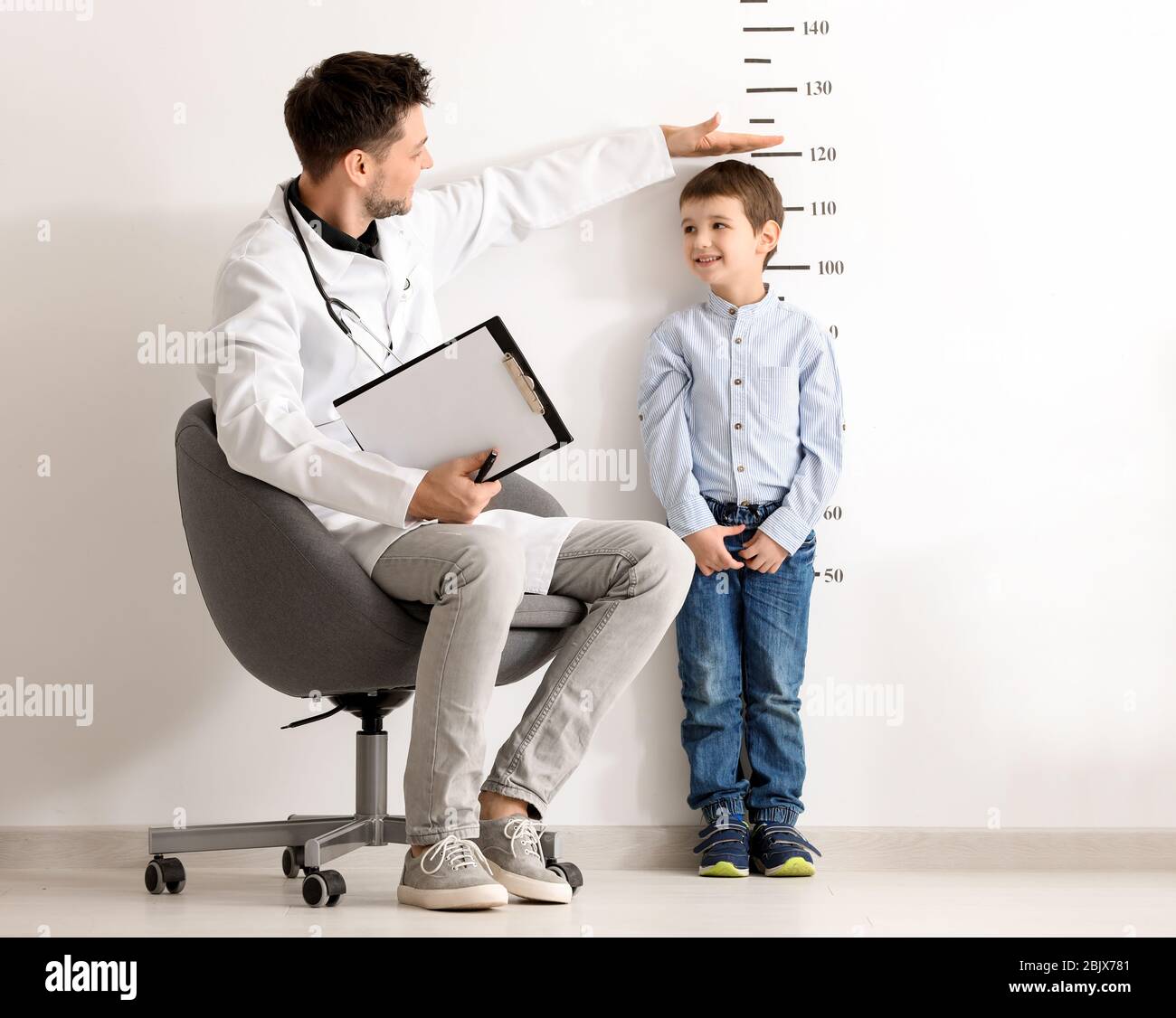 Male doctor measuring height of little boy in clinic Stock Photo