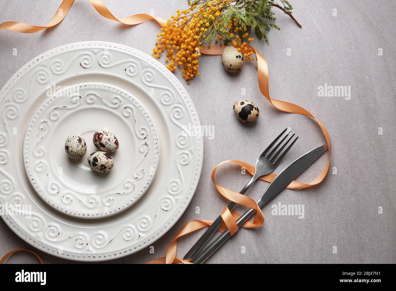 Beautiful festive Easter table setting with mimosa and quail eggs Stock Photo