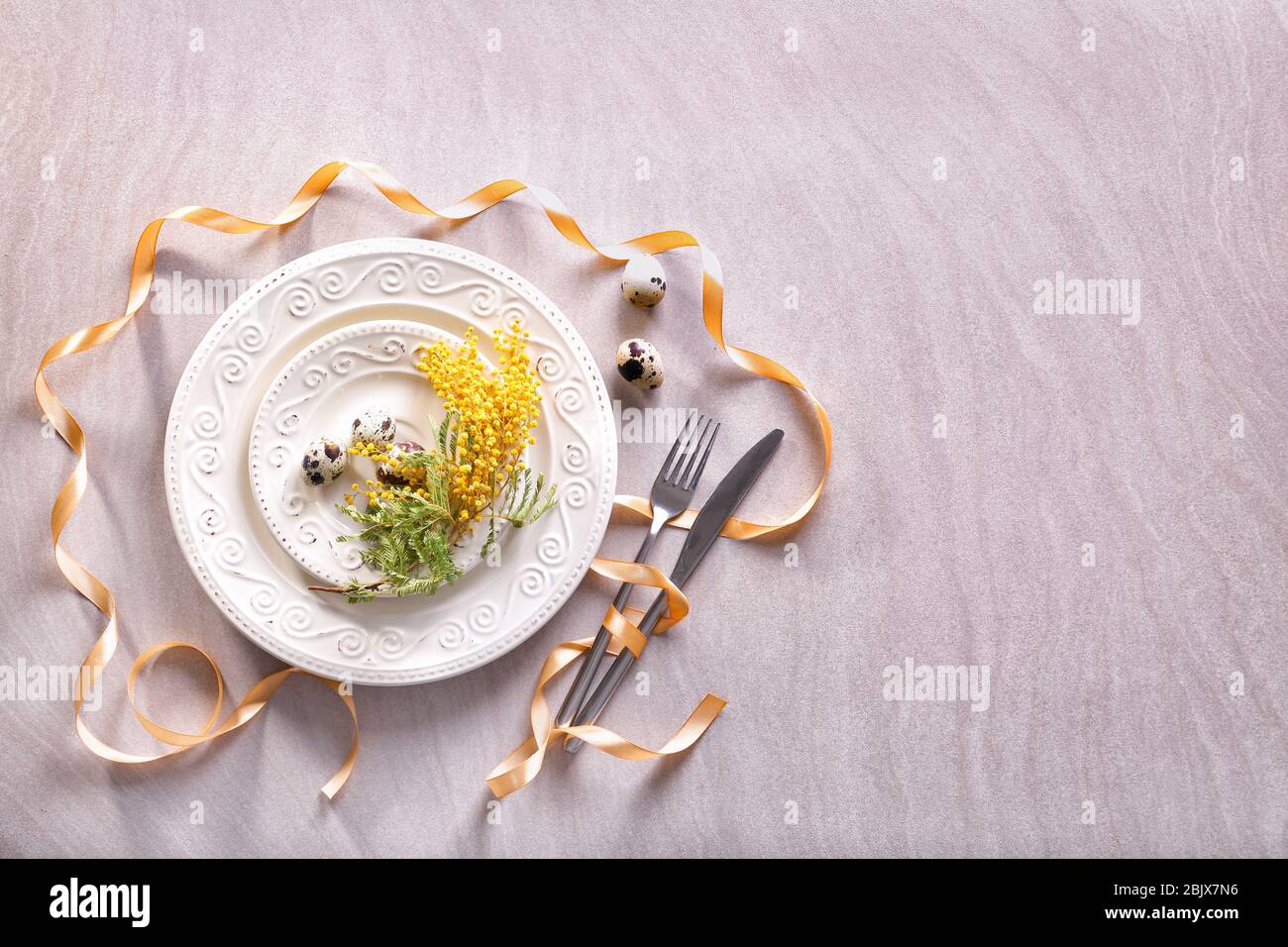 Beautiful festive Easter table setting with mimosa and quail eggs Stock Photo