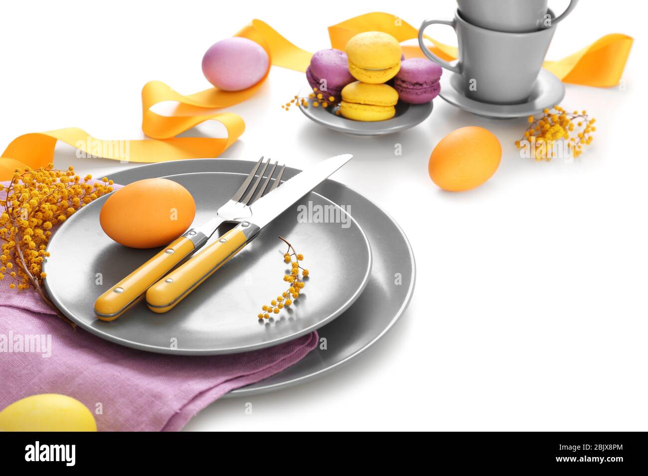 Beautiful festive Easter table setting with mimosa and painted eggs on white background Stock Photo