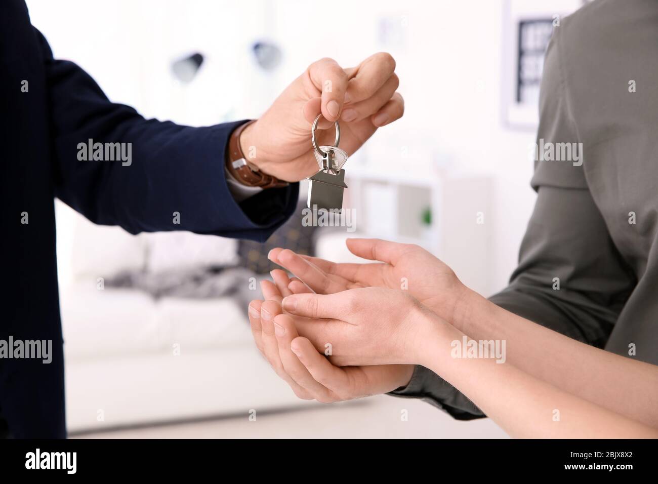 Real estate agent giving house key to young couple indoors Stock Photo ...