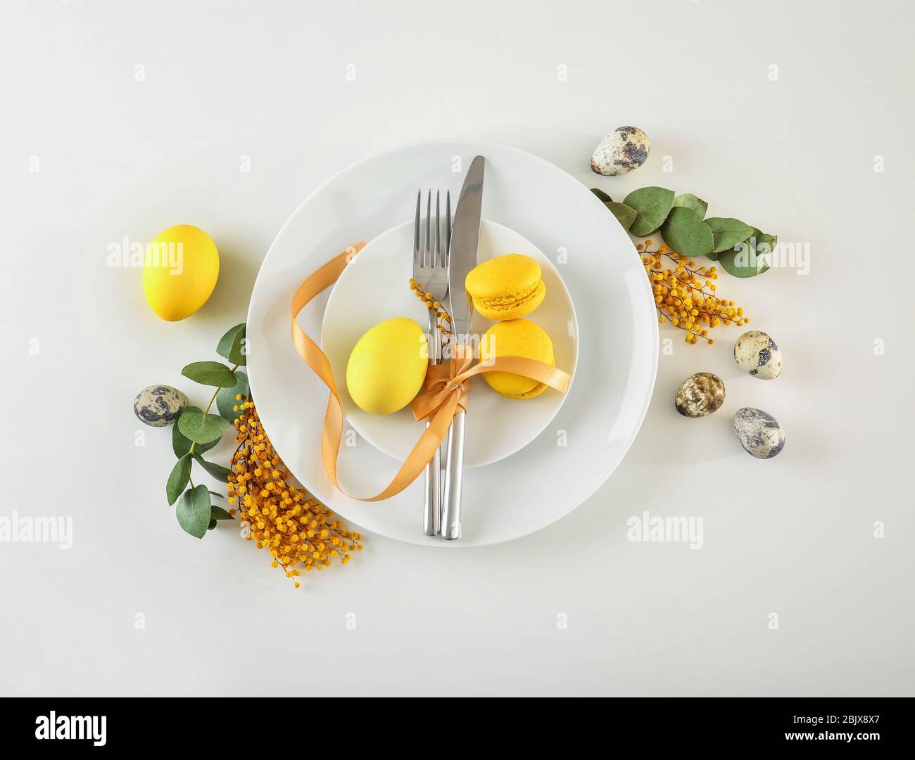 Beautiful festive Easter table setting with mimosa and eggs on white background Stock Photo