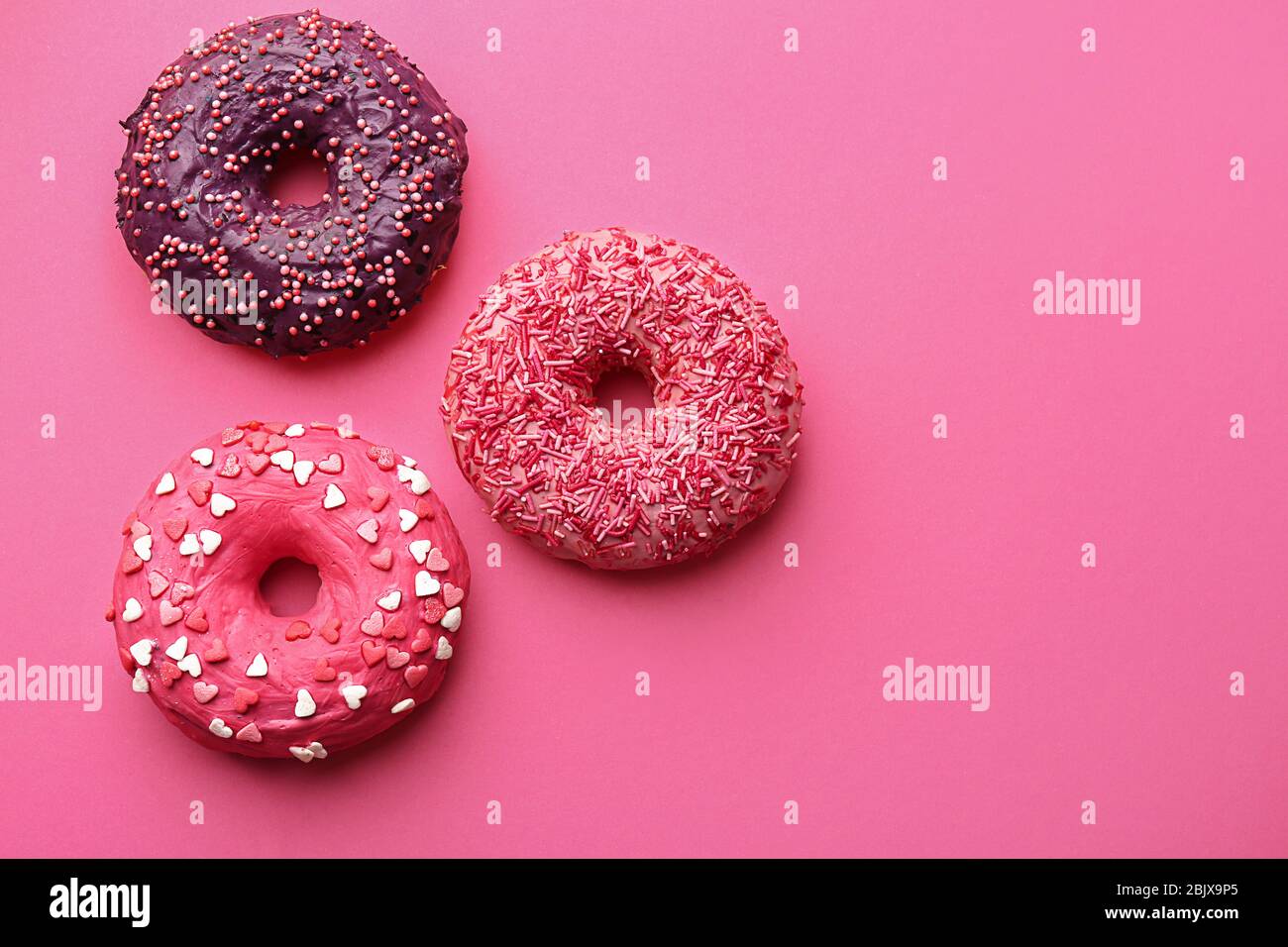 Delicious colorful donuts on color background Stock Photo - Alamy