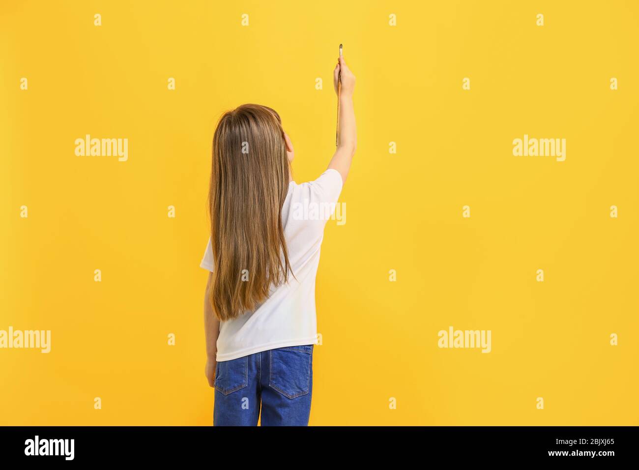 Little girl painting on color wall Stock Photo Alamy