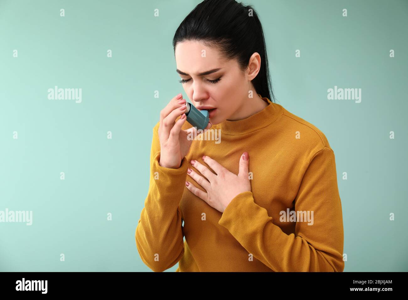Young woman having asthma attack on color background Stock Photo - Alamy