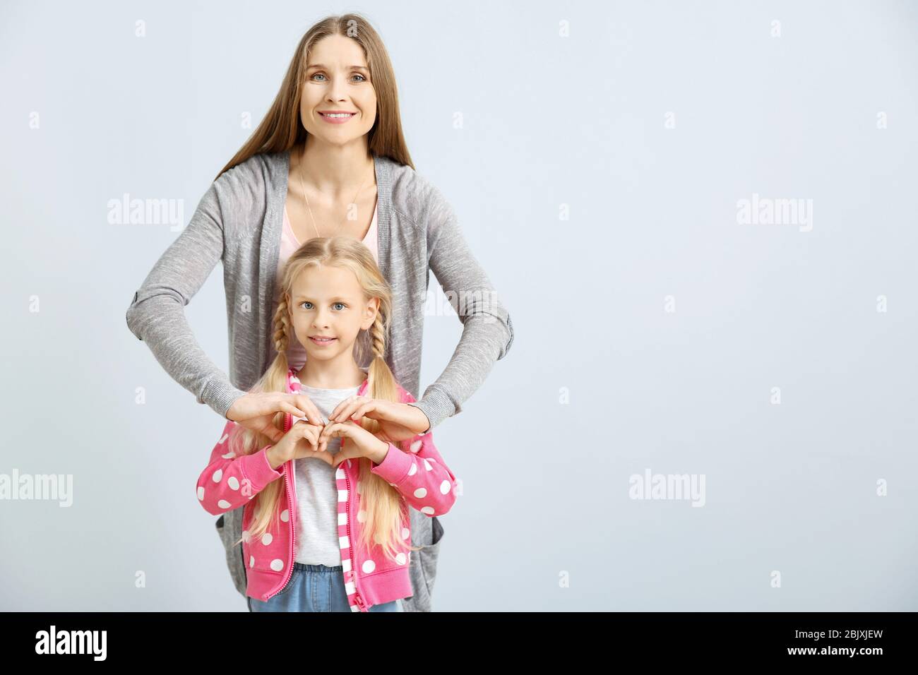 Little deaf mute girl and her mother using sign language on light