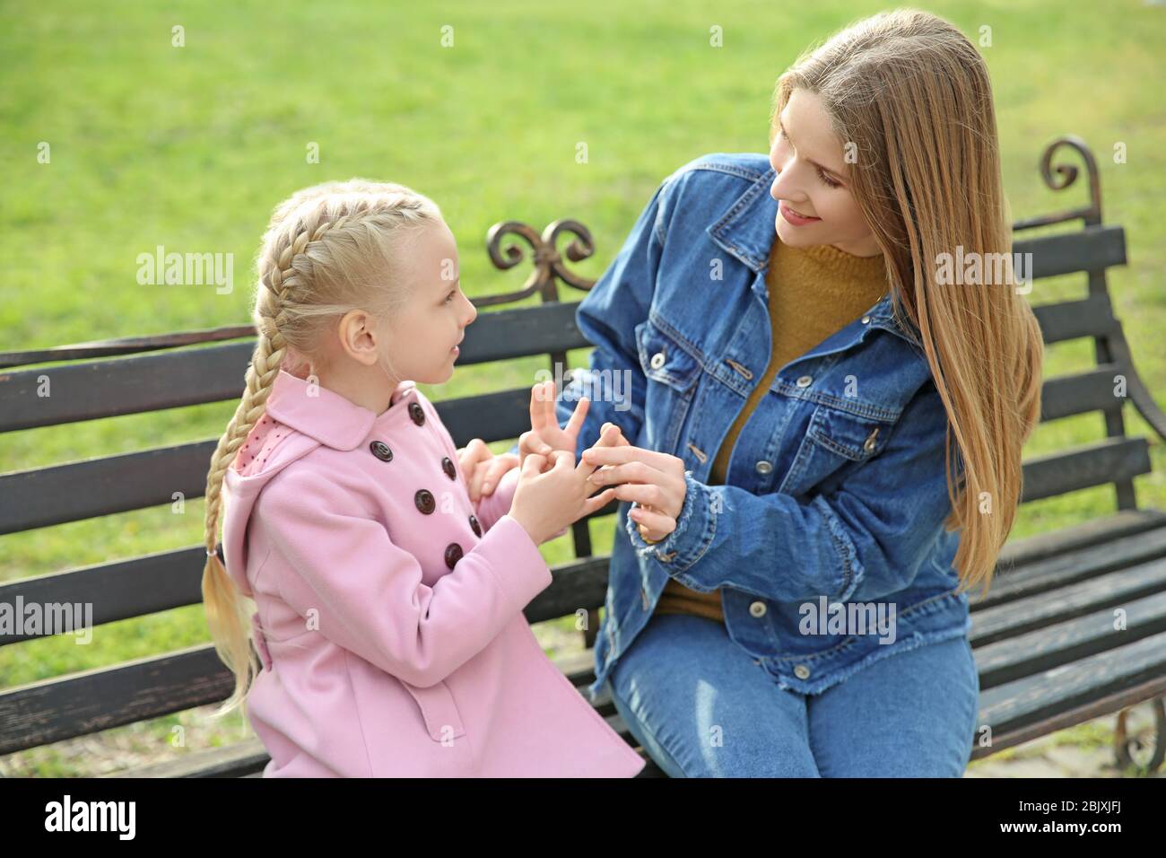 Mother teaching her deaf mute daughter to use sign language outdoors