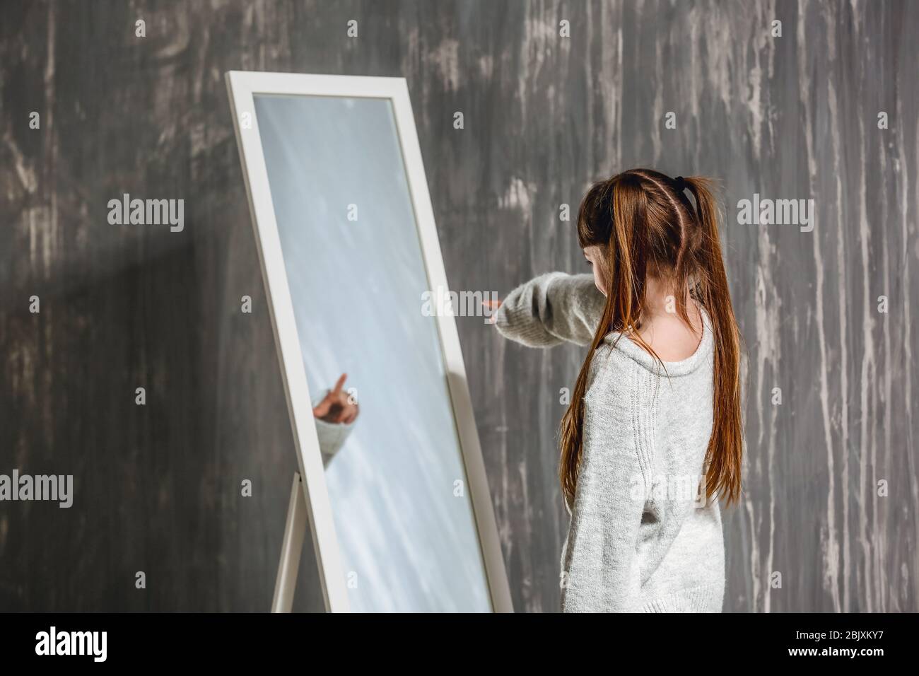 Little girl with autistic disorder looking into mirror on grunge