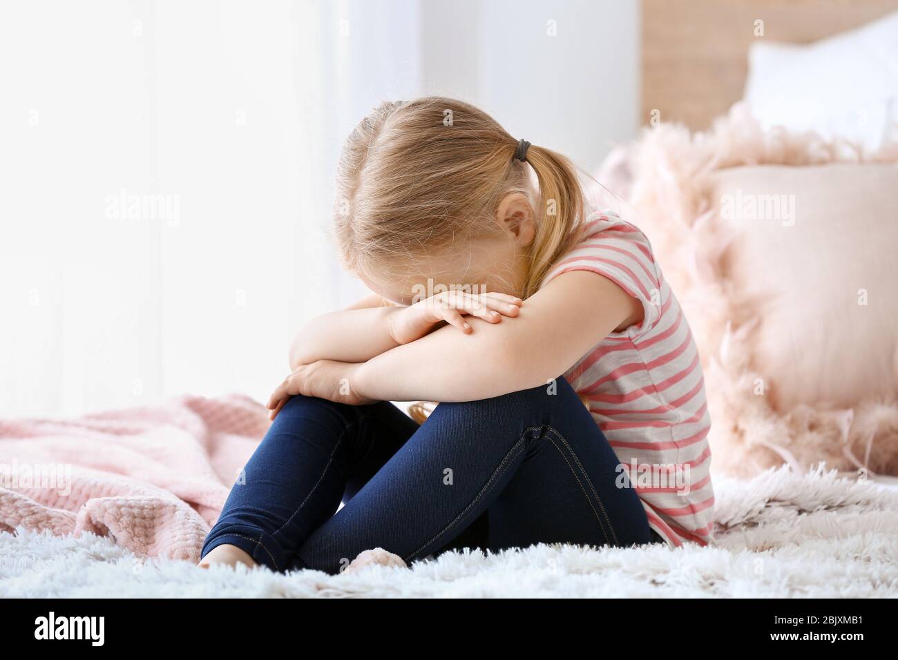 Crying little girl sitting on bed Stock Photo Alamy