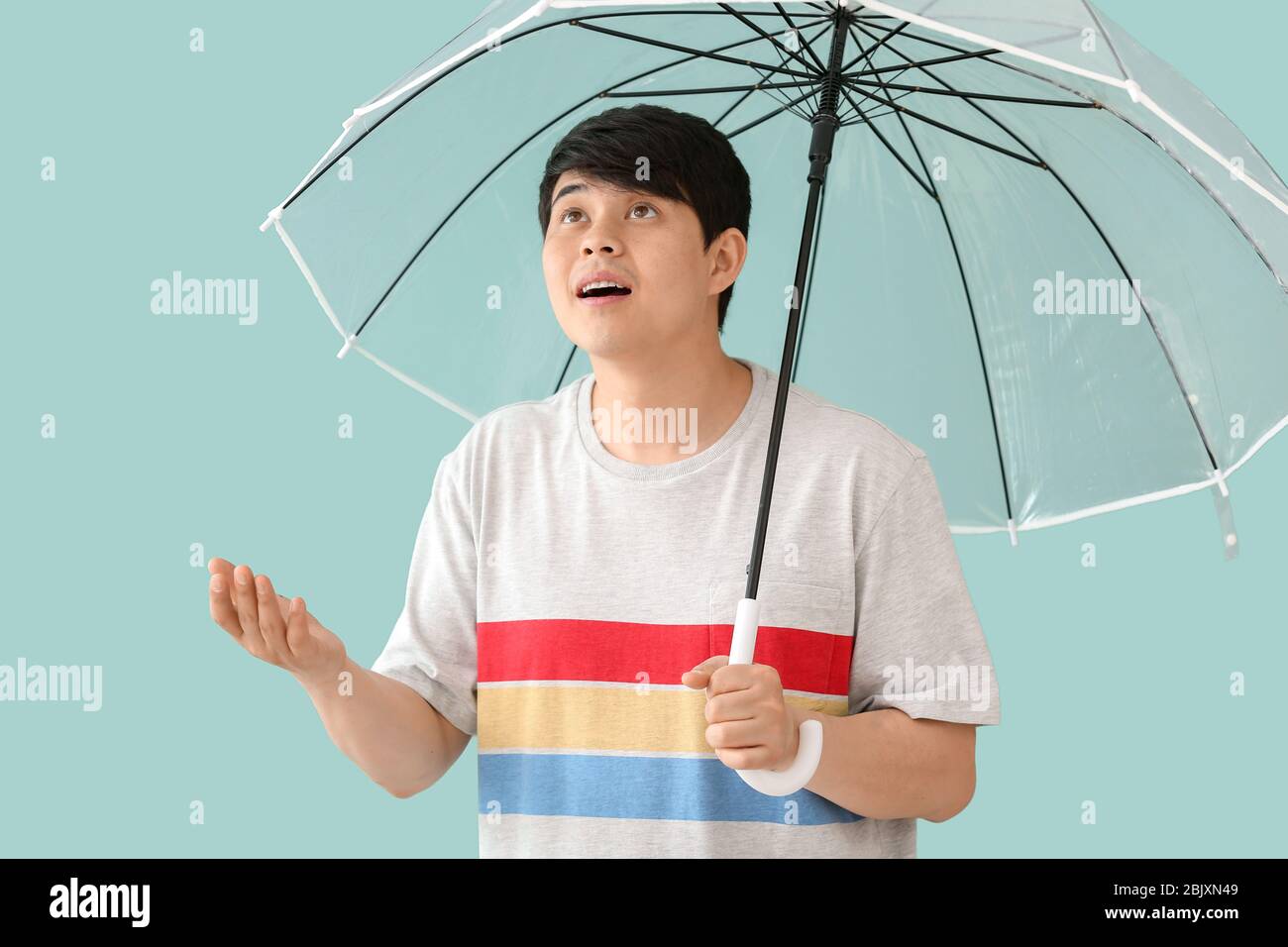 Handsome Asian man with umbrella on color background Stock Photo - Alamy