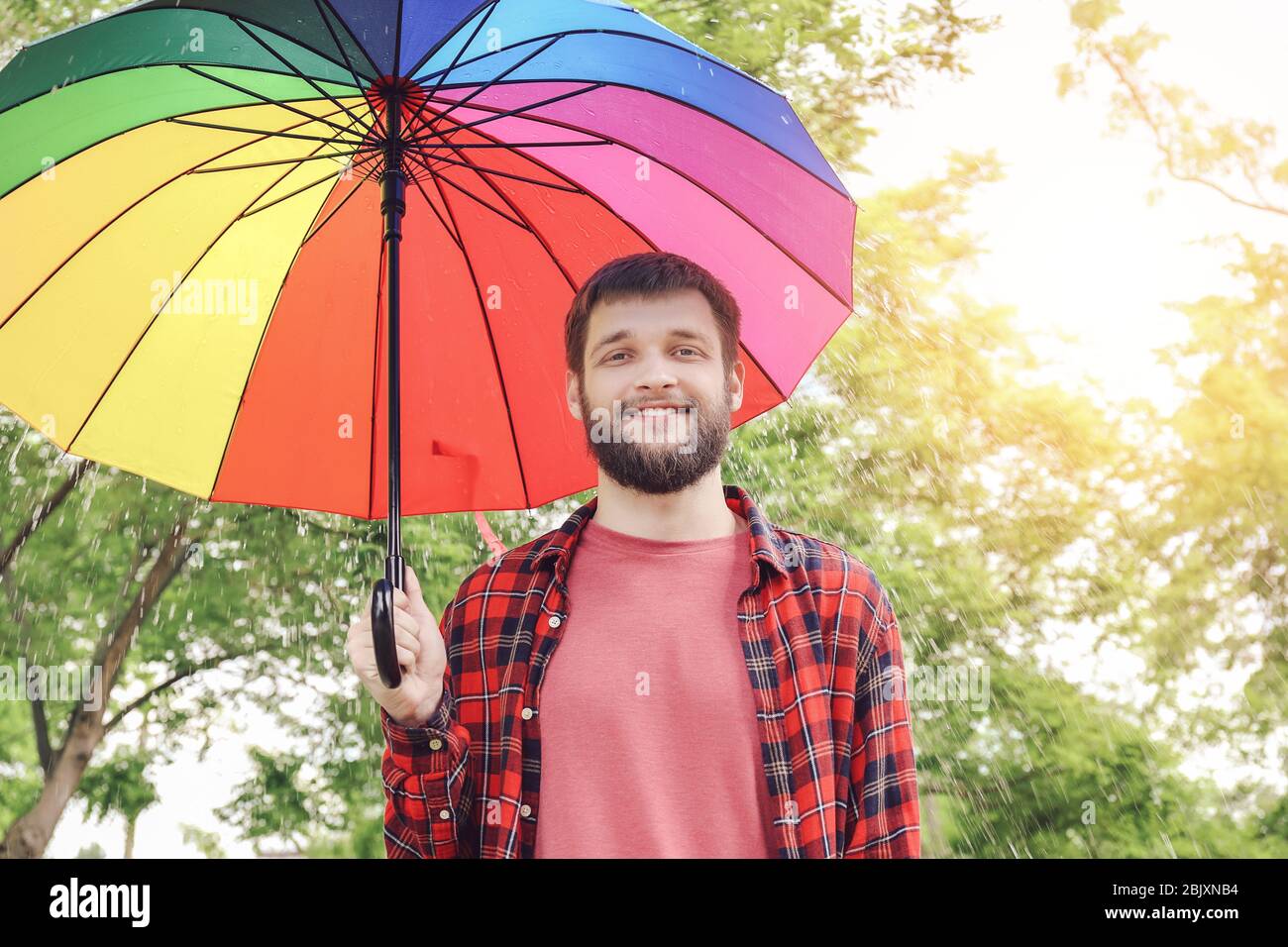 Handsome man with colorful umbrella outdoors Stock Photo - Alamy