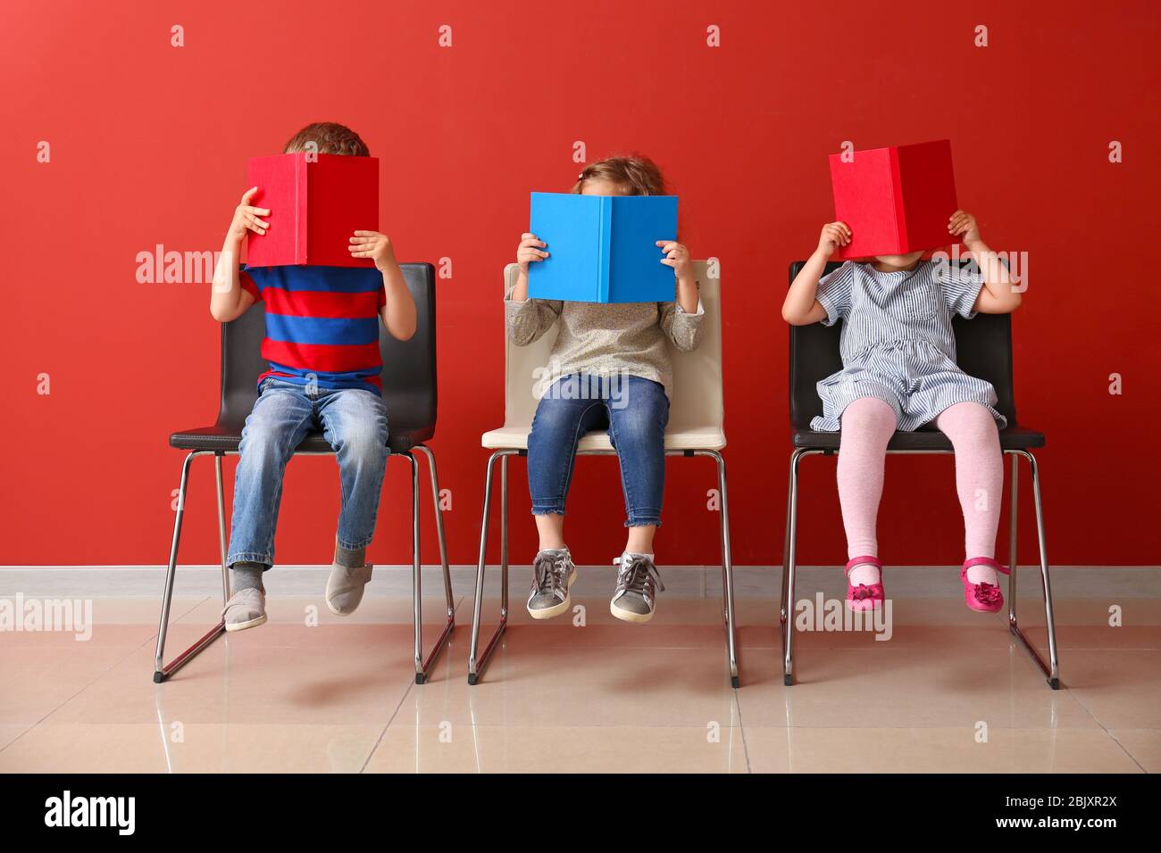 Cute little children reading books near color wall Stock Photo Alamy