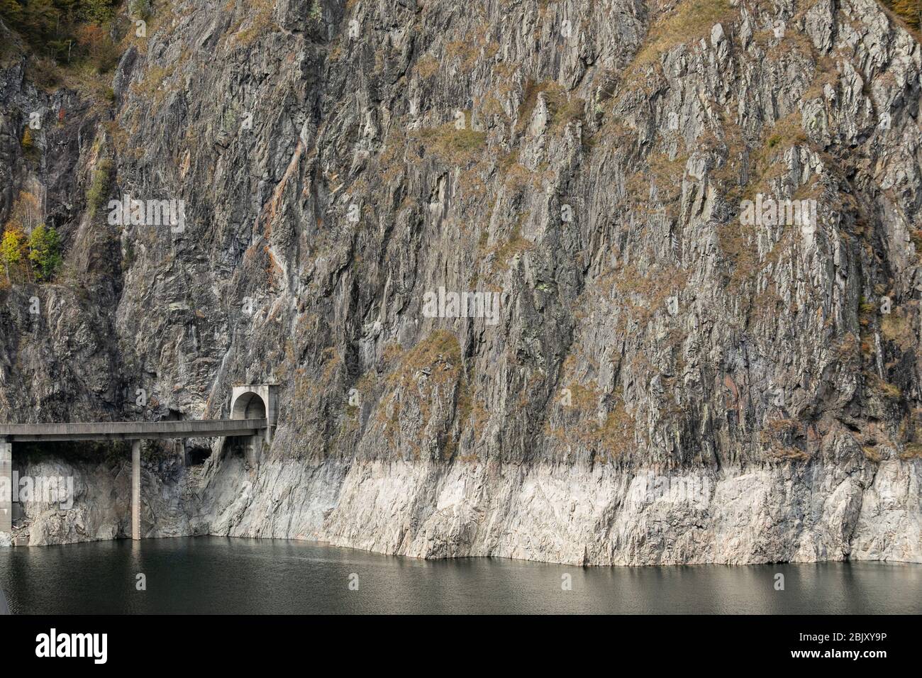 road and tunnel in steep granite stone cliff rock on vidraru lake