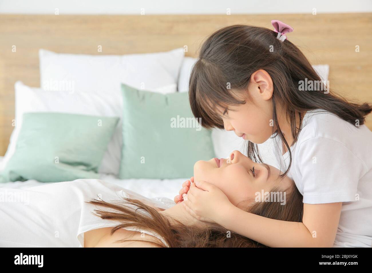 Little girl with her mother on bed at home Stock Photo Alamy