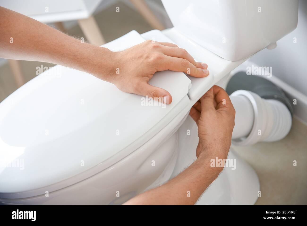 Plumber installing toilet in restroom Stock Photo Alamy