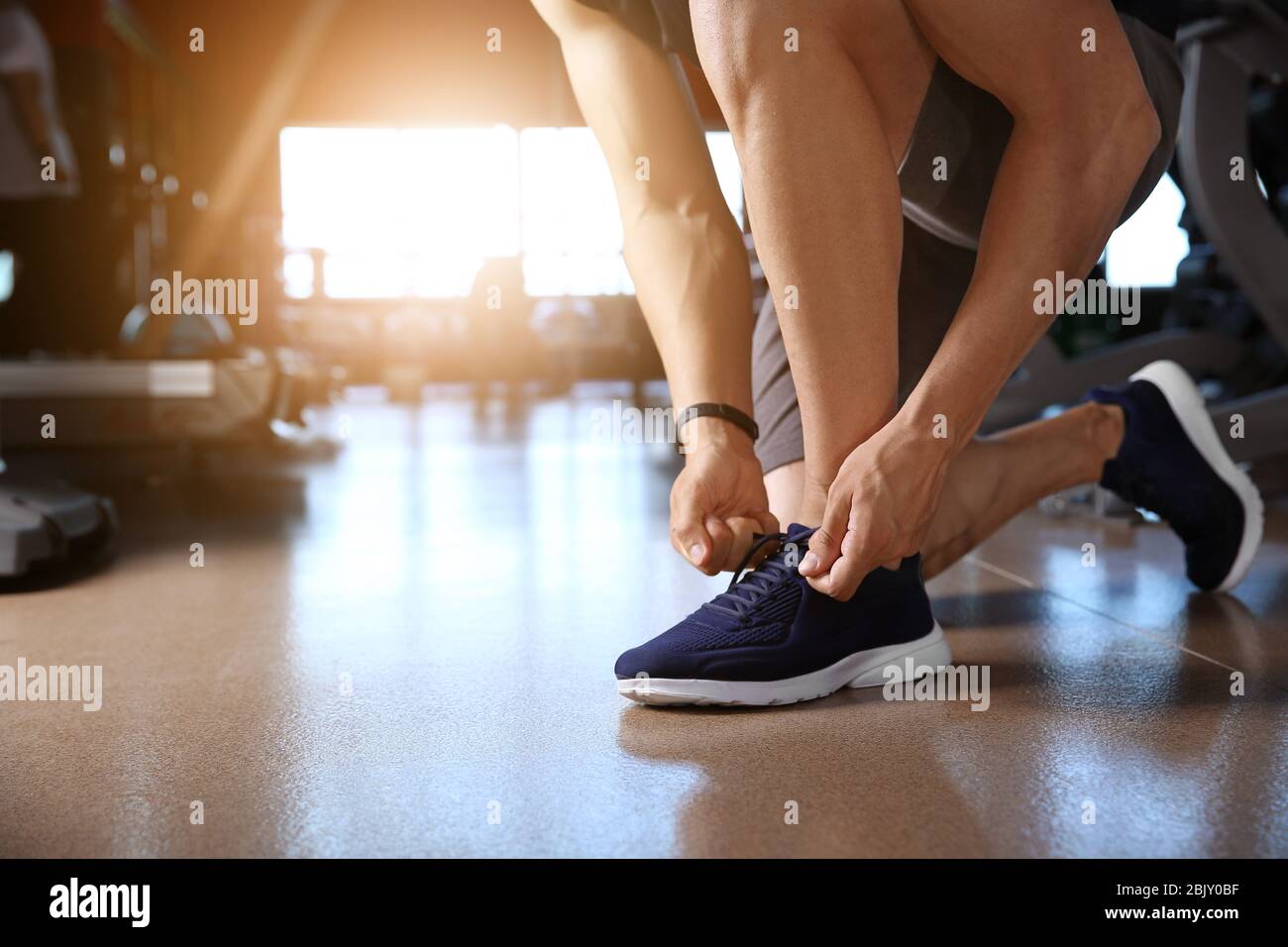 Image showcasing Sporty young man tying shoelaces in gym Stock Photo - Alamy
