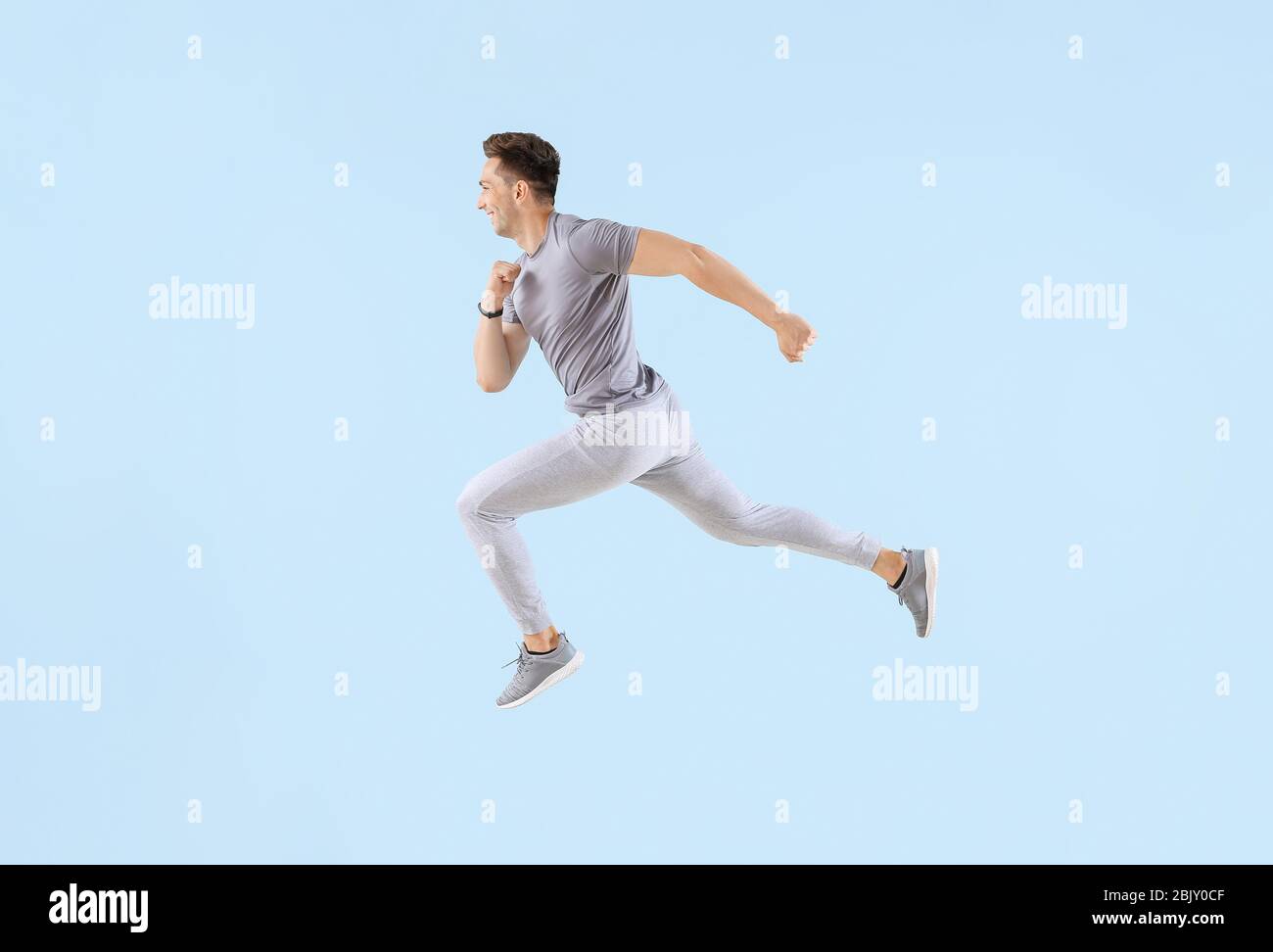 Running young man on color background Stock Photo - Alamy