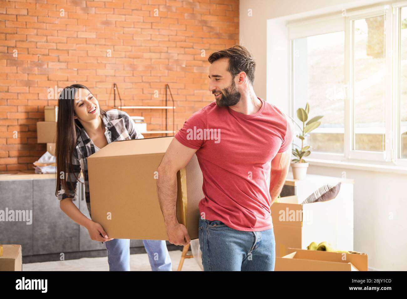 Young couple carrying boxes after moving into new house Stock Photo - Alamy