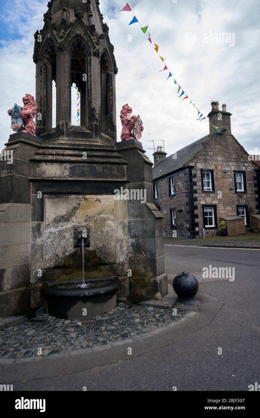 Bruce Fountain with festive colored flags above it, site of famous Outlander tv series scene when Jaime's ghost watches Claire in the adjacent inn win Stock Photo