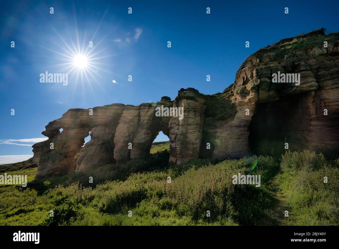 Sunstar above the Caiplie Caves, or Coves, rock formation along the North Sea on the Fife Coastal Path, Crail, Scotland, Europe Stock Photo