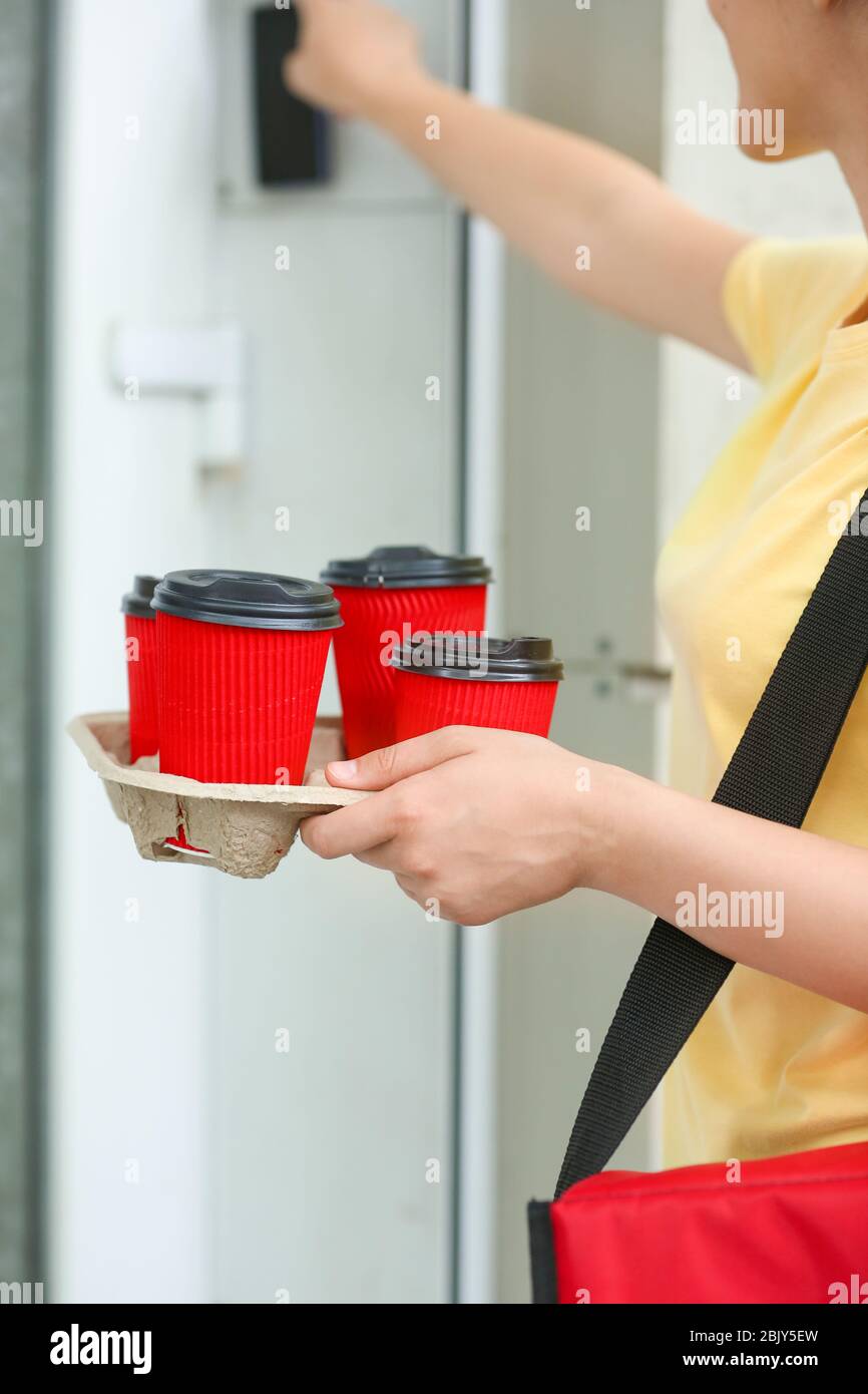 Female worker of food delivery service ringing doorbell Stock Photo