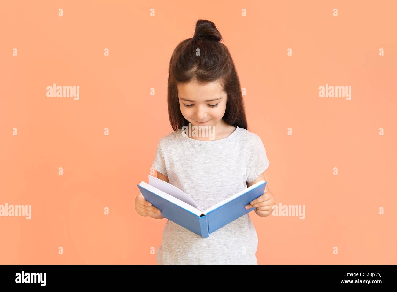 Cute little girl with book on color background Stock Photo - Alamy