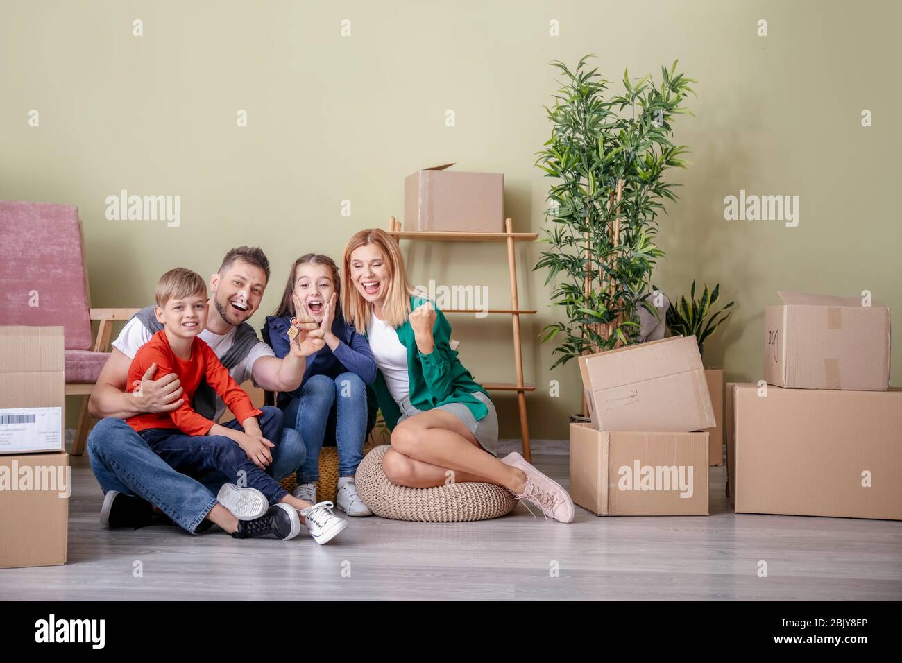 Happy family with belongings and keys in their new house Stock Photo ...