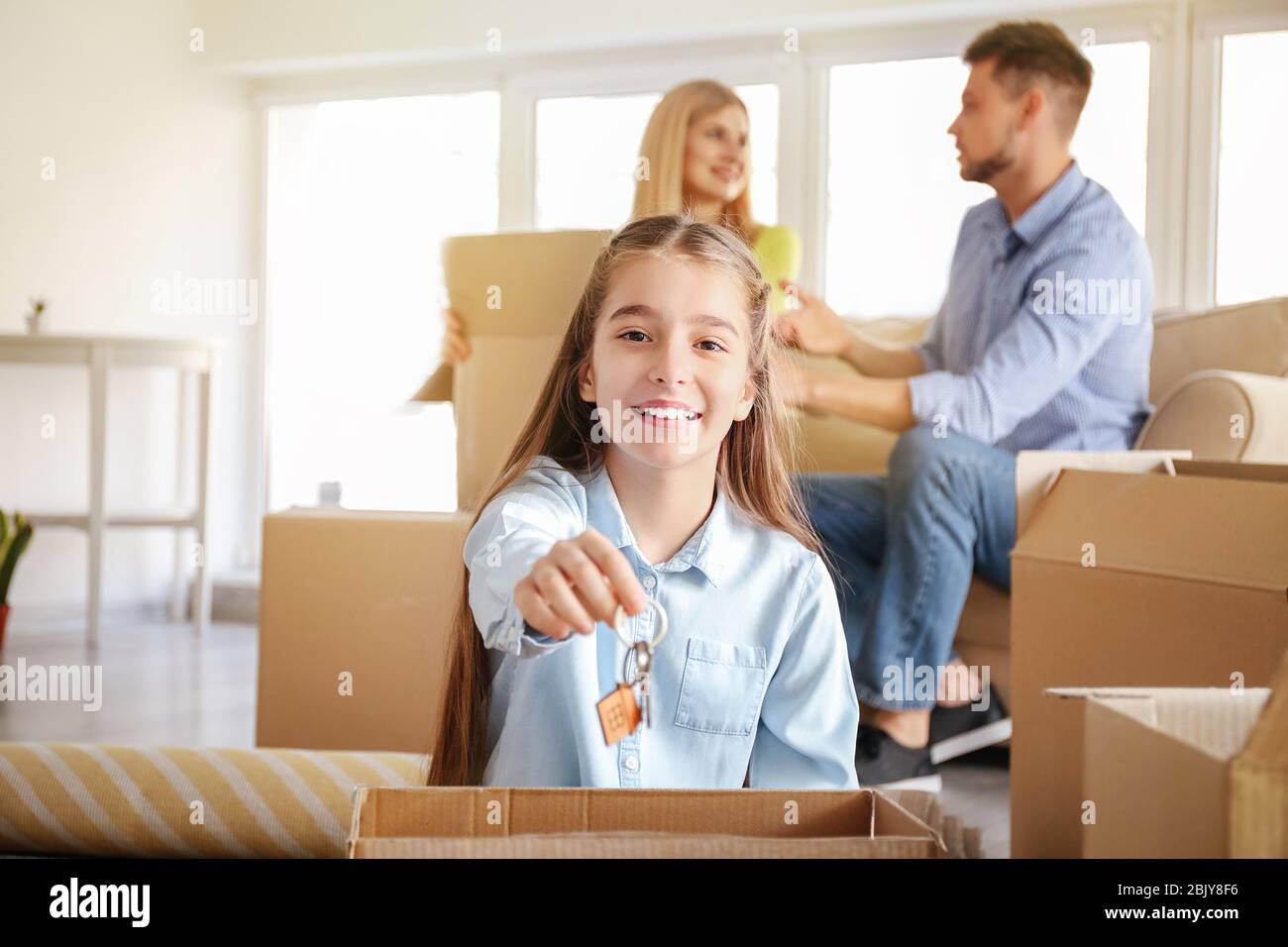 Happy girl with keys and her parents in new home Stock Photo - Alamy