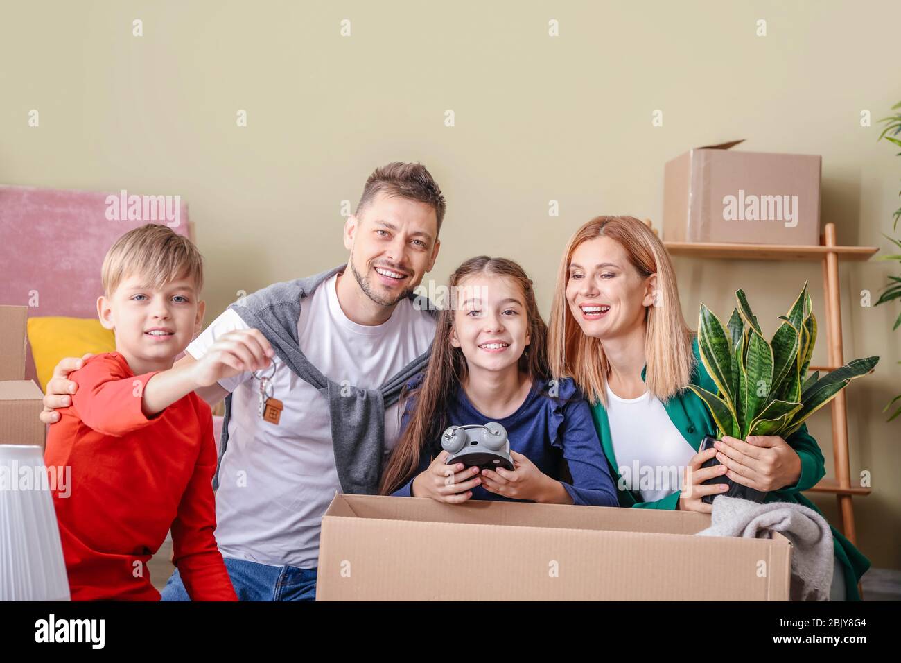 Happy family with belongings and keys in their new house Stock Photo ...