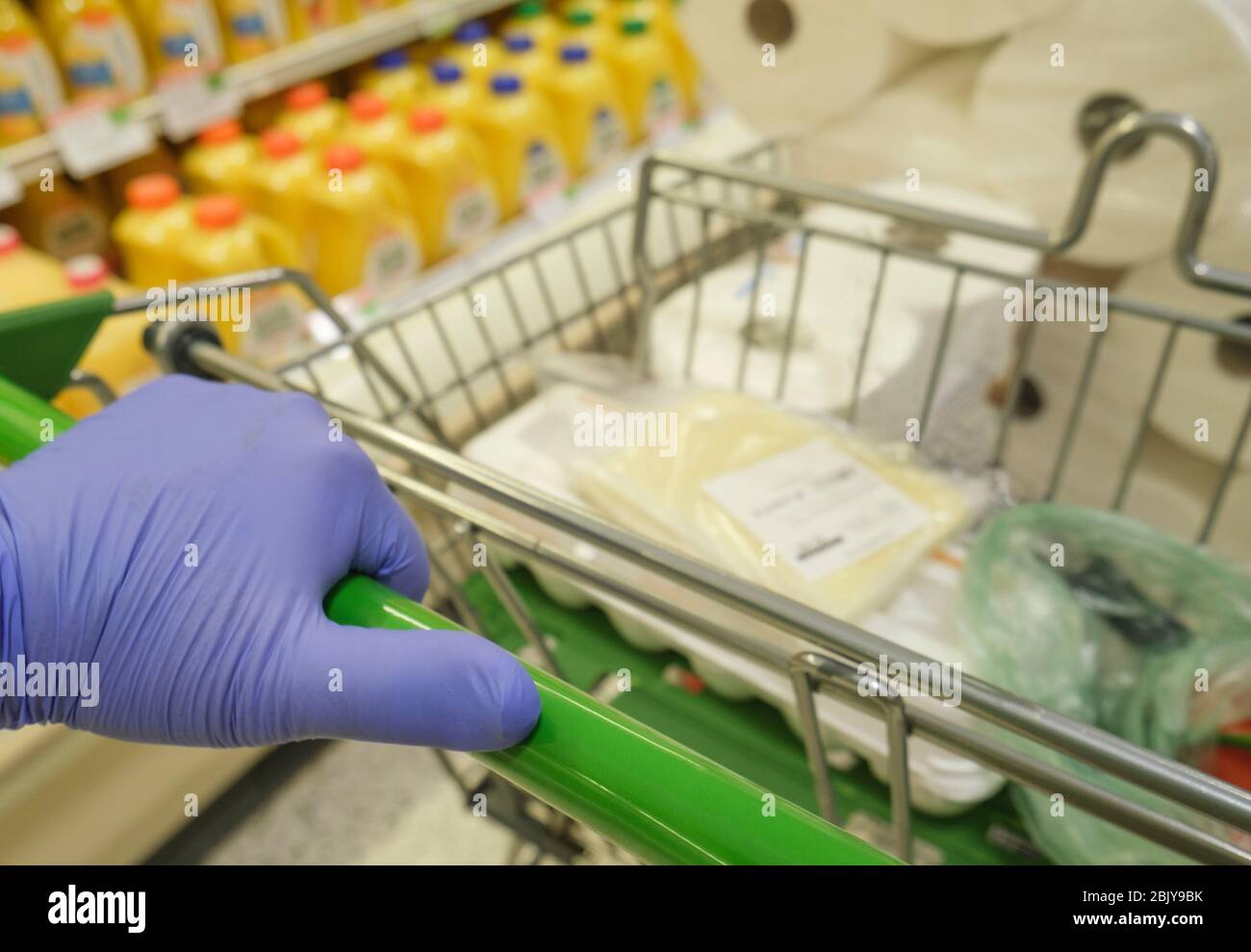 Close-upÂ of gloved hand pushing shopping cart in grocery store Stock Photo