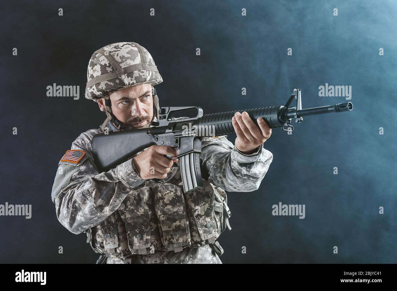 Soldier in camouflage taking aim on dark background with smoke Stock ...