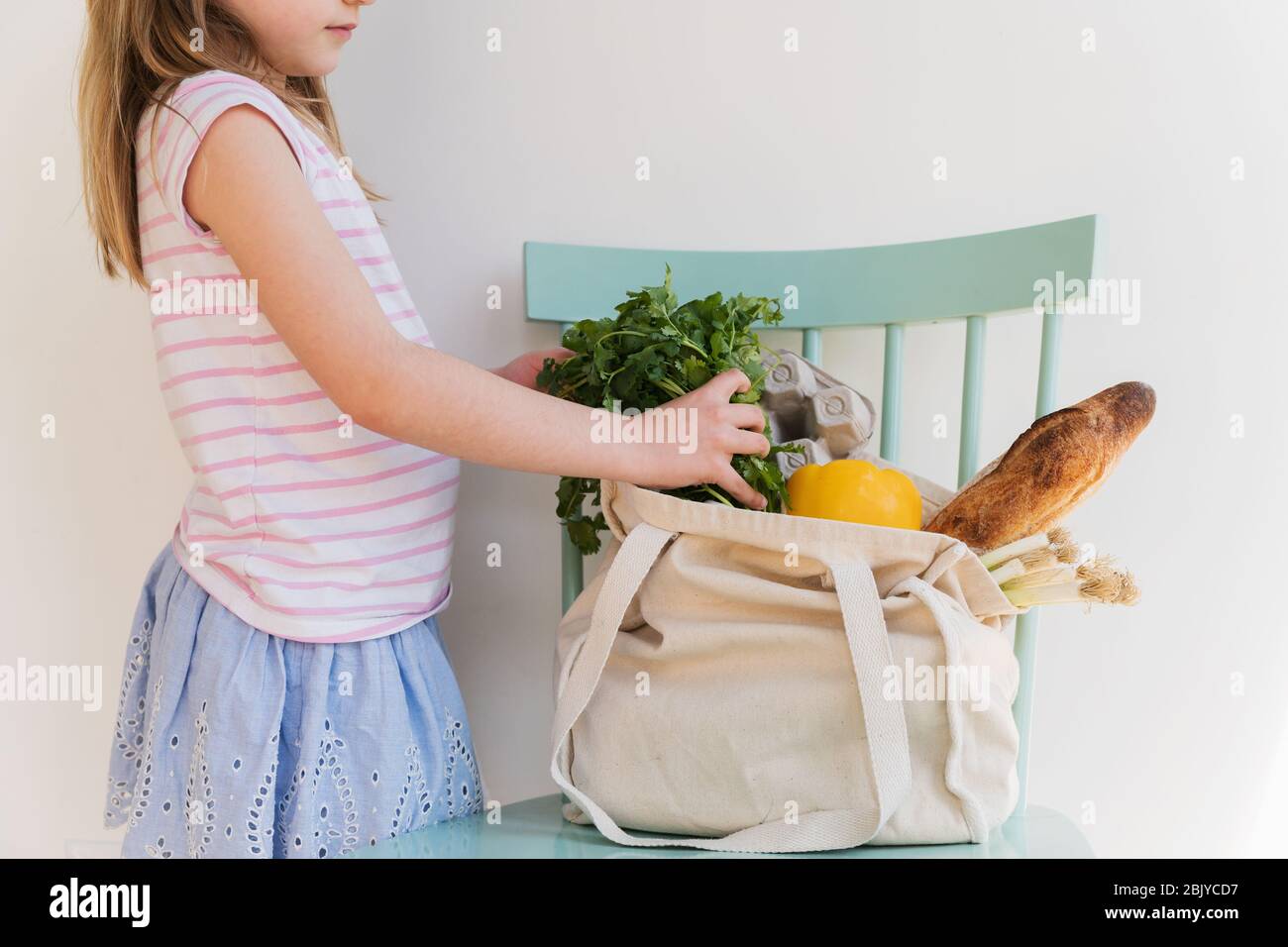Girl unpacking products from reusable bag Stock Photo