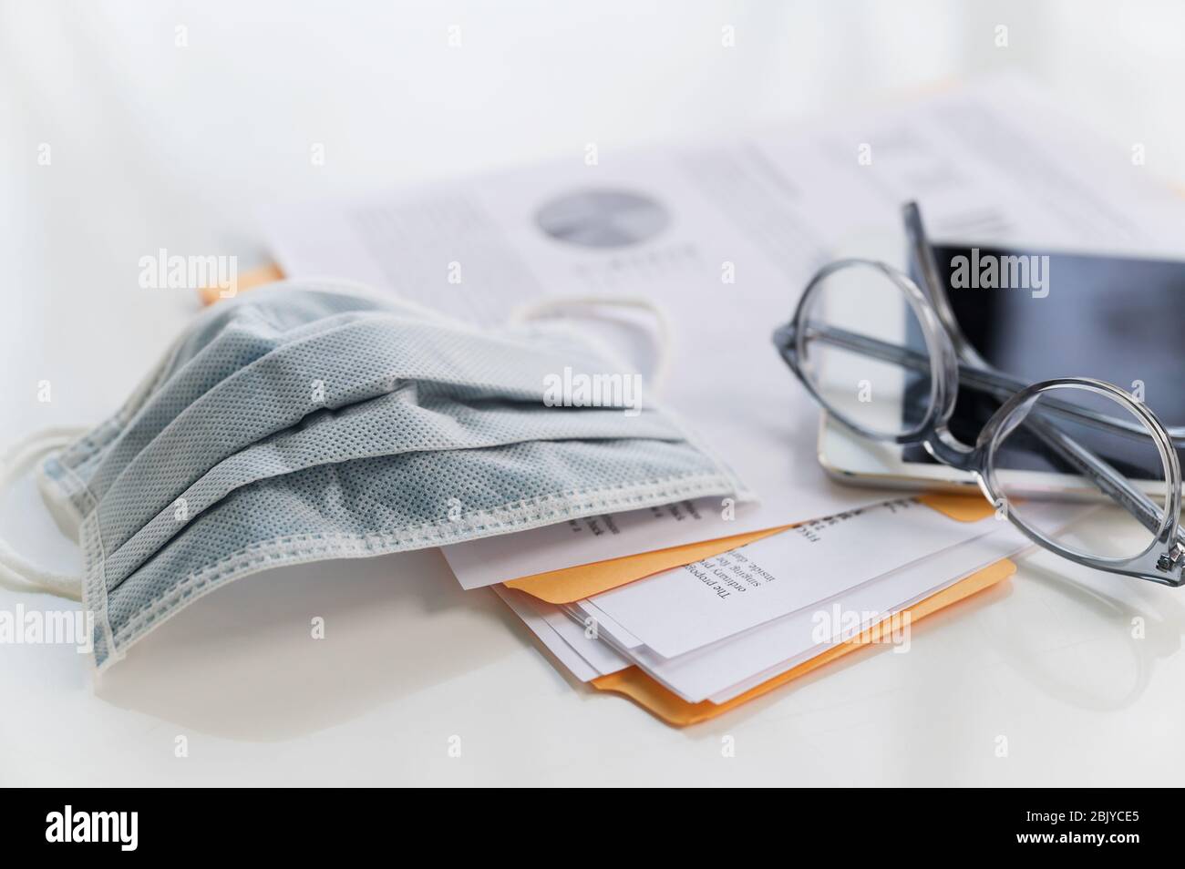 Face mask on business papers and tablet Stock Photo