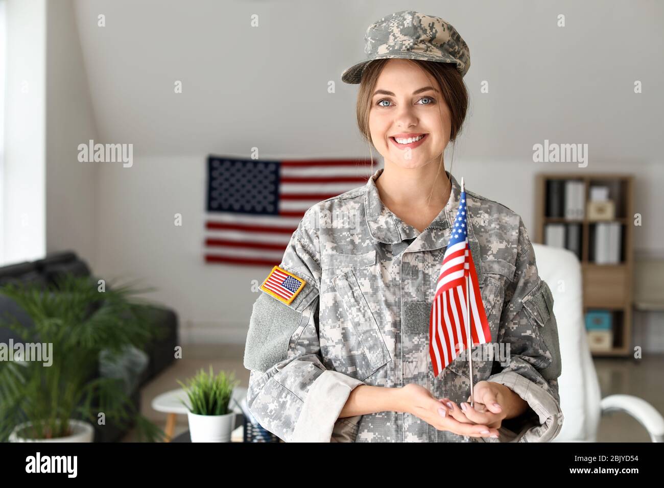 Young female soldier with USA flag in headquarters building Stock Photo ...