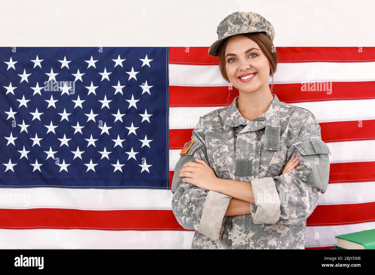Young female soldier near wall with USA flag in headquarters building ...