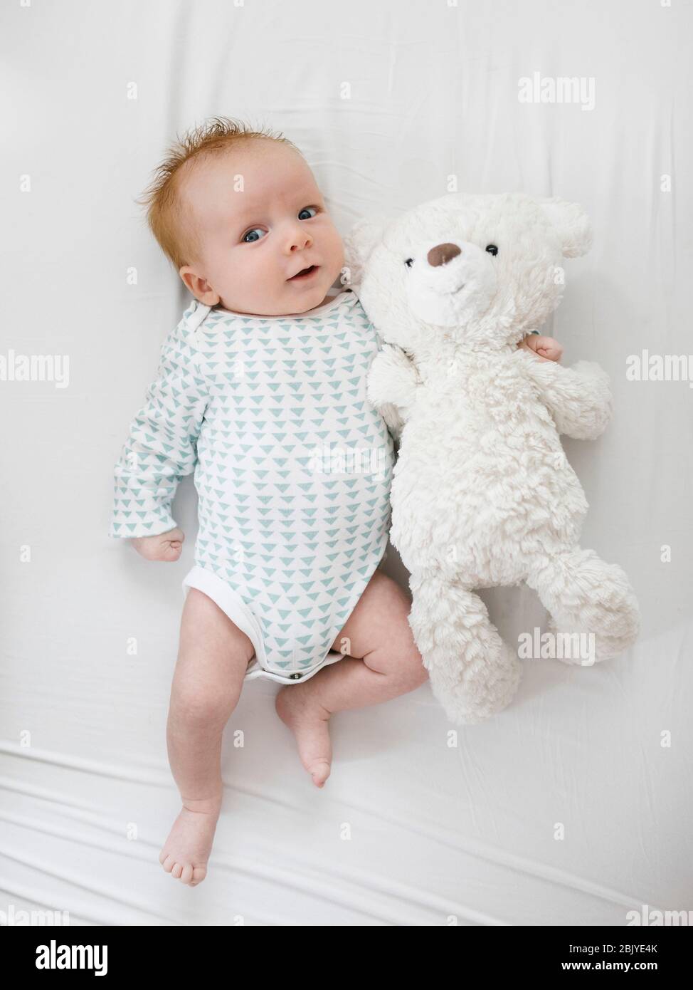 Baby boy (2-5Â months)Â lying on bed with teddy bear Stock Photo