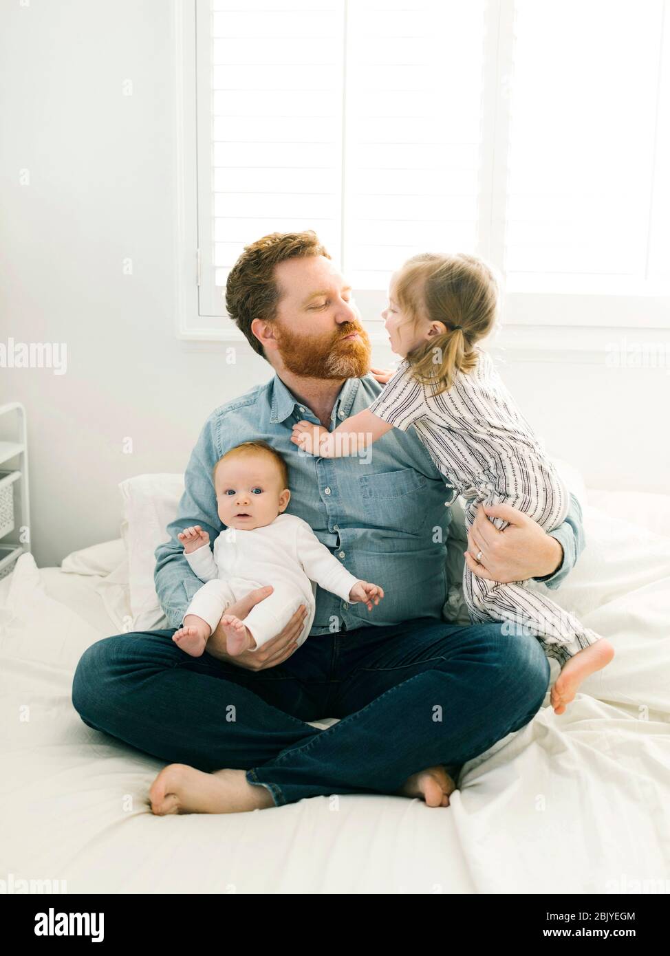 Father sitting on bed with children (2-3 months, 2-3) Stock Photo